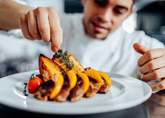 A chef with some arange fruit on a plate